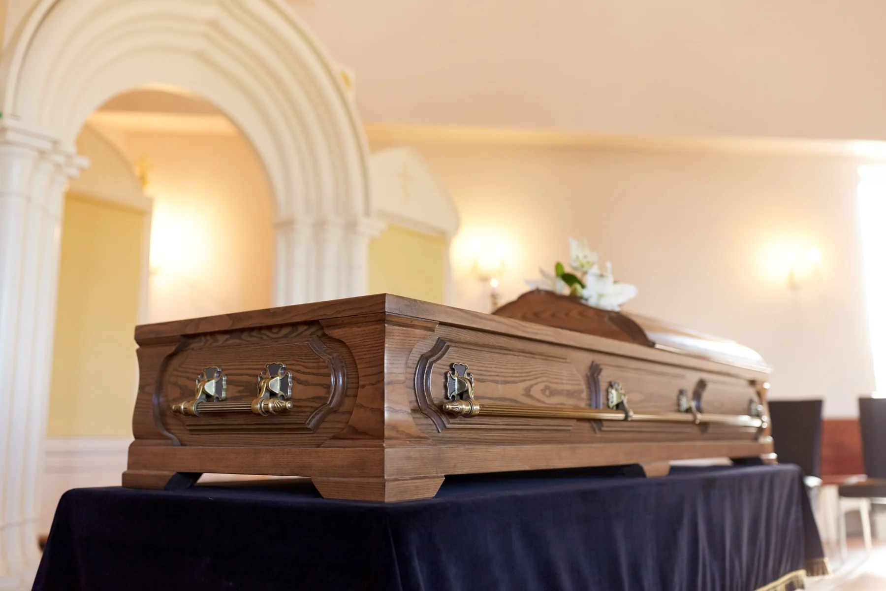 Oak casket in a softly lit chapel with arched walls